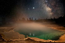 Black Pool thermal pool with Milky Way in night sky above, West Thumb Geyser Basin, Yellowstone National Park, Wyoming, USA. July, 2020.