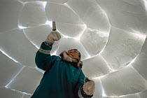 Inuit man building igloo using saw, Admiralty Inlet, Nunavut, Canadian Arctic.