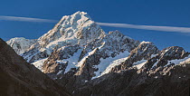 Mount Cook, highest mountain in New Zealand, with aeroplane vapour trail across the sky behind, South Island, New Zealand, April.