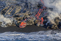 Glowing lava entering the Pacific Ocean causing eruptions of steam as surf collides with molten rock, Volcanoes National Park, Hawaii. August, 2010.