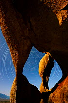 Triple Arch eroded granite formation at night against star trail rotating around the North Star, Alabama Hills, Eastern Sierra, California, USA. May.