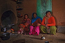 Three Indian women preparing meals on indoor open stove, Chausali, near Almora, Uttarakhand, India. March, 2012.