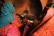 Two Indian women cooking over an open wood fire, in their home, Chausali, near Almora, Uttarakhand, India. March, 2012.