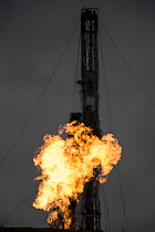 A rush of natural gas is aflame at new oil well. Flaring off gas is a major source of CO2 emissions, methane and black soot, Bakken oil field, North Dakota, USA. October, 2013.