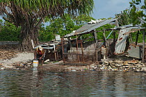 Man picking through waste floating into his village during high water levels and flooding caused by the 'King Tides', Fongafale, Tuvalu, Pacific Ocean. February, 2011.