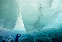 Photographer Gary Braasch inspecting the inside wall of an ice cave in a terminus of the Marr Ice Piedmont, Anvers Island, Antarctica. January, 2000. This ice cave, which revealed the glacier's m...
