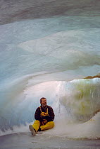 Photographer Gary Braasch sitting inside an ice cave in a terminus of the Marr Ice Piedmont, Anvers Island, Antarctica. January, 2000. This ice cave, which revealed the glacier's marble-like inte...