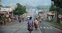 People on motorcycles riding down centre of smoky street, Davao, Mindanao, Philippines, March 2007.