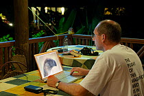 Photographer Klaus Nigge editing photos of Philippine eagle (Pithecophaga jefferyi) on laptop, Malagos, Davao, Mindanao, Philippines, August 2006.