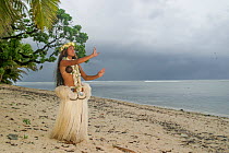 Polynesian woman in traditional dress performing dance on beach, Rarotonga, Cook Islands, South Pacific. September, 2017. Model released.