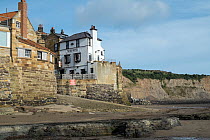 View of hotel next to a slipway in Robin Hoods Bay at low tide, North East Yorkshire, England, UK. September.