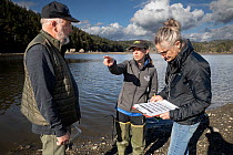 Three volunteers with the European Green Crab invasive species research site planning a beach survey, Chuckaut Pocket Estuary, Washington, USA. April, 2023.