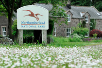 Northumberland National Park roadside sign containing the emblematic image of a curlew, Kirknewton Village, Northumberland National Park, Northumberland, England, UK. June, 2014.