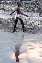 Man working at Lake Katwe salt works, Queen Elizabeth National Park, Uganda. February, 2023. Saline water is evaporated from dug earthen ponds to produce rock salt and 'muddy' salt used for...
