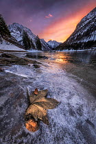 Frozen lake and snow-covered mountains at sunset, Lago di Predil, Julian Alps, Italy. February, 2023.