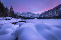 Snow-covered lake and mountains at sunset, Lago di Fusine, Julian Alps, Italy. February, 2023.