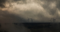 Wind turbines spinning as low cloud envelops them, Scottish Highlands, UK.