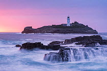 View of Godrevy lighthouse at high tide with colourful afterglow at dusk, Gwithian, West Cornwall, UK. May, 2022.