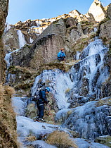 Mountaineers ice climbing on frozen waterfalls on Red Screes above Kirkstone Pass, Lake District, Cumbria, UK. December, 2022.