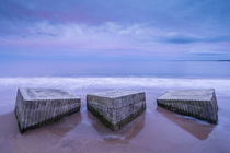 Tank blocks from World War 2, along the shoreline on beach at sunset, Alnmouth beach, Northumberland, UK. October 2023.