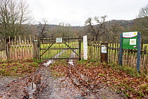Sign beside gated entrance to Moccas Park National Nature Reserve, with park pale made up of internal ditch and a wooden fence, Herefordshire, England, UK, December 2023. Wooden fence made from cleft...