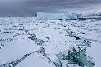 Iceberg amongst sea ice under dark sky, Coulman Island Area, Ross Sea, Antarctica. February, 2023.