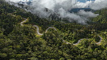 A mountain road winding through rainforest on the slopes of the Arfak Mountains, West Papua, Indonesia. June, 2023.