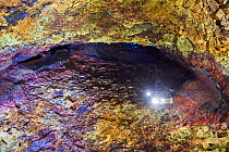 Colourful rocks inside the magma chamber of Thrihnukagigur volcano with torch light from an open cable lift. Yellow is sulfur oxide, grey and black is basalt rock and green is copper. Rust-red colorat...