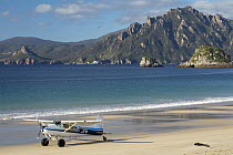 Transport plane on the beach runway of Codfish Island with the Ruggedy Range of Stewart Island in the background, Whenua Hou / Codfish Island, New Zealand. April, 2019.