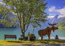Wooden Moose sculpture and bench looking over Oldedalen valley on the southern shore of the Nordfjorden, Vestland county, Norway. June, 2021.