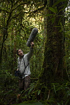 Man holding microphone recording bird calls as part of documentation of the biodiversity of the Foja Mountains. Montane forest at approx 1650 m elevation, West Papua. November, 2008.