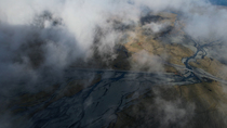 Aerial shot, above the clouds, of dry glacier river, south Iceland. June. Sequence 2/2.