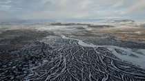 Aerial panning shot of frozen braided glacial river, south Iceland. February.