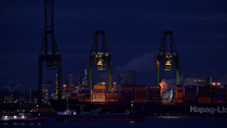 Container terminal at night, showing gantry cranes stacking containers on ship docked along the Western Scheldt, Port of Antwerp, Flanders, Belgium. 2023.