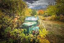 Abandoned old Soviet era truck surrounded by autumn foliage under stormy sky, Rhodpe Mountains, Bulgaria. October, 2023.