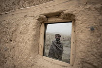 Afghan farmer standing outside traditional hut, Afghanistan. October, 2023.