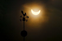 Partial solar eclipse above silhouette of weather vane, Wroclaw, Poland. 3rd March, 2015.