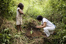 Local man and boy geotagging a recently planted Caoba tree (Swietenia macrophylla), part of the reforestation project, Sierra Nevada de Santa Marta, Colombia. December, 2021.