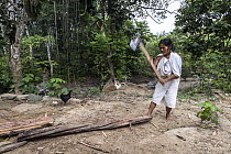 Woman from the Wiwa community cutting wood for cooking in village, El Encanto, Sierra Nevada de Santa Marta, Colombia. December, 2021.