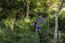 Man carrying crate of saplings and holding a shovel preparing to plant trees as part of a reforestation project, Sierra Nevada de Santa Marta, Colombia. December, 2021.