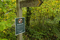 'No foraging' sign under public footpath signpost, Ebernoe Common Nature Reserve, Sussex, England, UK. November, 2023.