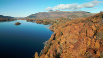 Drone shot of Derwentwater and its wooded edges. In the background is the Skiddaw mountain range. Keswick, Lake District National Park, Cumbria, UK.