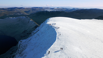 Drone shot of hikers on Helvellyn summit. This peak is the third highest in the Lake District National Park. Cumbria, UK.