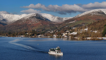 Drone tracking shot of ferry leaving Ambleside town, Lake Winderemere, Lake District National Park, Cumbria, UK.
