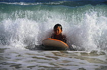 Young boy bodyboarding in the shallows off Diamond Head, Hawaii.