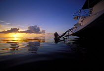 A woman reboarding the boat after swimming at sunset in the Abaco Islands, Bahamas, Caribbean.