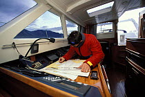 The skipper of "Shaman" in the cabin, using charts to navigate the isolated region of Spitsbergen, Svalbard, Norway, 1998.