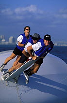 Three crew of a capsized 21 foot Viper one-design keelboat, balancing on the keel in an attempt to right the boat.