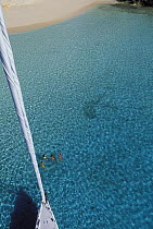 Aerial view from the masthead of the 88 foot sloop "Shaman", swimmers can be seen below in the clear waters of the Vava'u Group, Tonga, South Pacific.