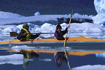 Couple kayaking through glacial ice in a tandem kayak in Alaska, USA. 2001